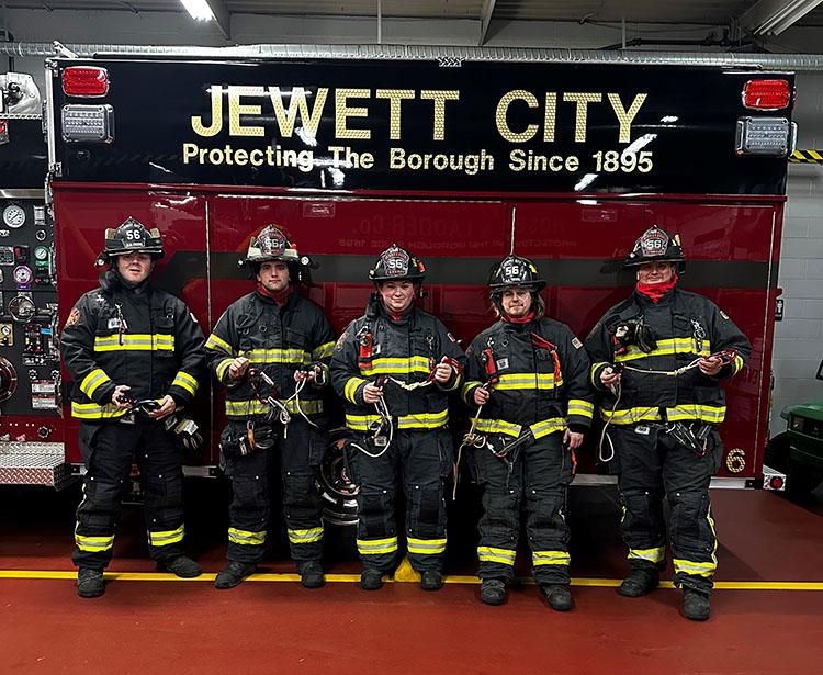 Five Jewett City Fire Department firefighters in full gear standing infront of a fire truck